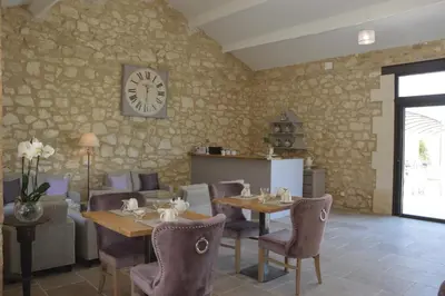 a restaurant with tables and chairs and a clock on the wall at Le Clos D'Olea in Oppède