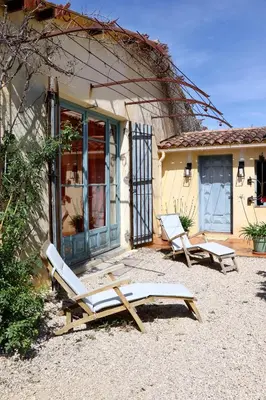 a couple of lounge chairs in front of a house at La Bastide des Vasses 