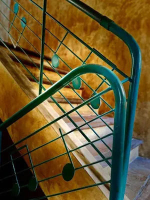 a green metal stair railing next to a wooden wall at La Sarrasine in Villes-sur-Auzon