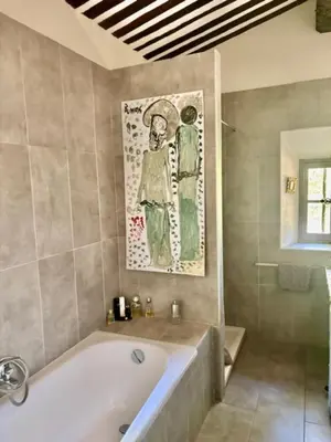 a bathroom with a tub and a painting on the wall at Stunning panoramic views and heated pool in Roussillon in Roussillon
