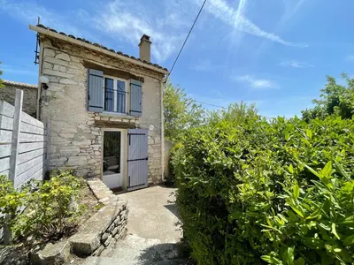 a stone house with a white door and some bushes at Gîte La Bastide de La Loge au pied du Mont Ventoux in Sault-de-Vaucluse