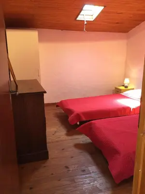a bedroom with two red beds and a wooden floor at typical provencal farm in an exceptional natural site, the alpilles park - 8 people. in Maussane-les-Alpilles