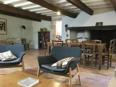 a living room with chairs and a table and a fireplace at typical provencal farm in an exceptional natural site, the alpilles park - 8 people. in Maussane-les-Alpilles