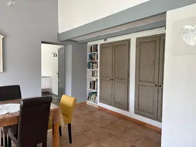 a dining room with a table and a book shelf at Le Mazet Des Joncs en Provence in Saint-Pierre-de-Vassols
