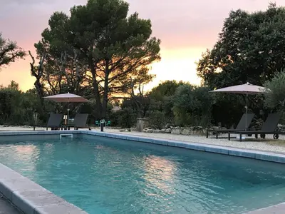 a swimming pool with two chairs and umbrellas at Mas la Chêneraie Lourmarin - Au calme, à 10 mn du centre ville à pied in Lourmarin