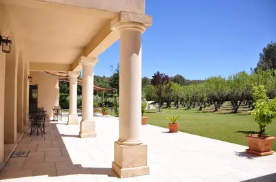 an outdoor patio with columns and a lawn at Le Jardin des Amandiers in Châteaurenard