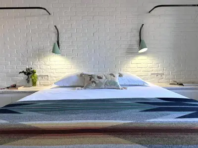 a bedroom with a large bed with a white brick wall at Le 40 in LʼIsle-sur-la-Sorgue