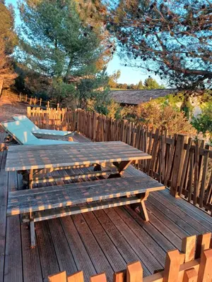 a wooden deck with a picnic table and a fence at Domaine de Villemus in Jouques