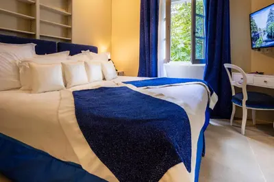 a bedroom with a blue and white bed with a desk at Le Clos Violette et Le 11 D'Aglaé - Appart' Hôtel de Charme Design de Luxe in LʼIsle-sur-la-Sorgue