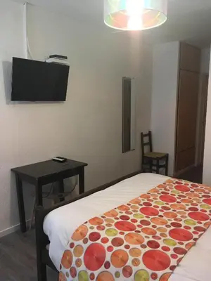 a room with a bed and a table and a television at Auberge de Rustréou in Rustrel