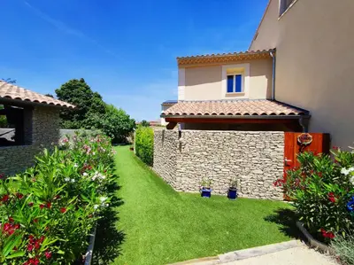a garden in front of a house with green grass at Au Murmure de la Sorgue in LʼIsle-sur-la-Sorgue
