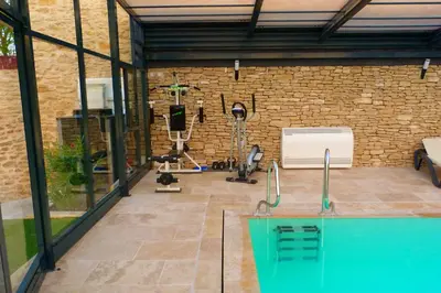 a gym with a swimming pool and a brick wall at Au Murmure de la Sorgue in LʼIsle-sur-la-Sorgue