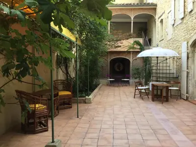 a patio with chairs and tables and an umbrella at Maison de village Novissime in Noves