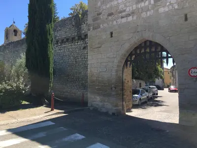 an archway in a stone wall with cars parked at Maison de village Novissime in Noves