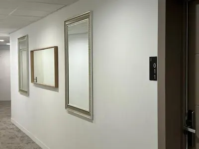 a hallway with three mirrors on a white wall at Le Néliö in Aix-en-Provence