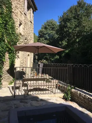a table with an umbrella next to a fence at La Calade, maison de village in Gordes