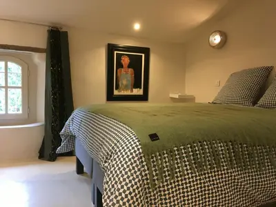 a bedroom with a bed and a clock on the wall at La Calade, maison de village in Gordes