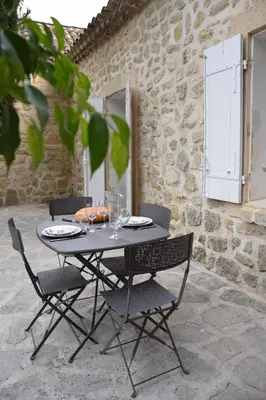 a black table with chairs and glasses on a patio at Moulin des Gypses Gîte Les Pierres Blanches, Ventoux in Mormoiron
