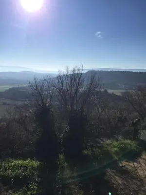 a view of a hill with the sun in the sky at Le Logis in Gordes