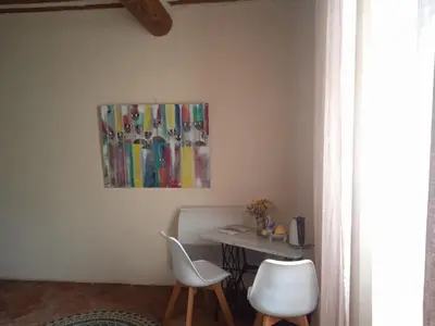 a table with two white chairs and a painting on the wall at Chambre d'hôtes face au lavoir in Méthamis