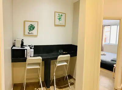 a room with a kitchen with a microwave and two stools at Victoire Appartement in Aix-en-Provence