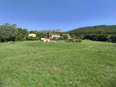 a large field of grass with a house in the background at Les Grandes Terres - Gîtes & SPA in Mérindol