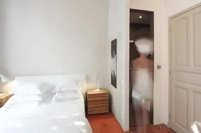 a bedroom with a white bed and a person in a closet at Maison Dauphine in Aix-en-Provence