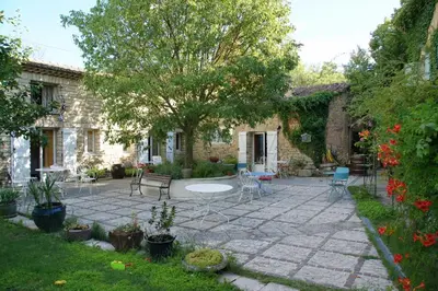 a patio with chairs and a tree in a yard at Moulin d'Antelon B&B in Crillon-le-Brave