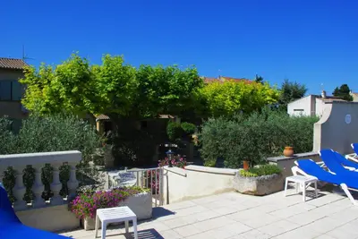a patio with blue chairs and a fence and trees at Gite le Mas de l'Amandier in Saint-Saturnin-lès-Avignon