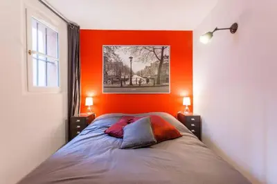 a bed in a room with an orange wall at L'Entrecasteaux in Aix-en-Provence