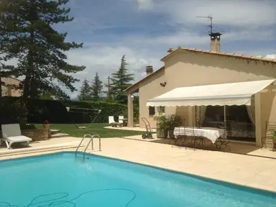 a swimming pool with a white umbrella and a house at Villa élégante à Céreste avec piscine privée et jacuzzi in Céreste