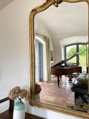 a mirror in a living room with a piano at Domaine de l'Enclos in Gordes