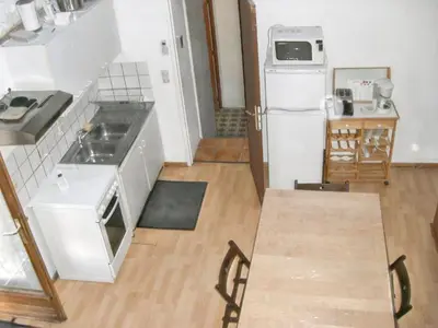a kitchen with a white refrigerator and a wooden floor at Maison charmante avec terrasse et jardin à Noves in Noves
