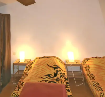 two beds in a room with two lamps on tables at Maison charmante avec terrasse et jardin à Noves in Noves