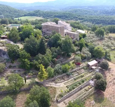 an aerial view of an old building on a hill with trees at Les Jardins de l'Abbaye in Simiane-la-Rotonde