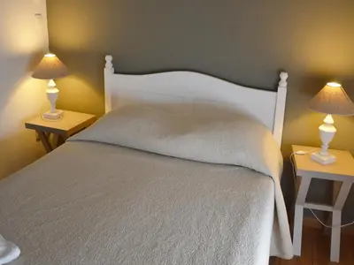 a bedroom with a white bed with two lamps on tables at Résidence Goélia Le Domaine du Moulin Blanc in Gordes