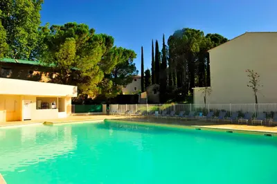 a large swimming pool with chairs and a fence at Résidence Goélia Le Domaine du Moulin Blanc in Gordes