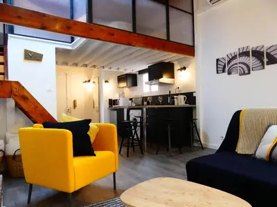 a living room with a yellow chair and a kitchen at Les Bernardines in Aix-en-Provence