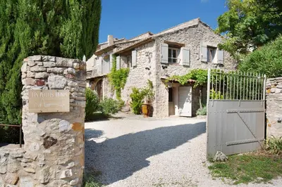 a stone house with a gate in front of it at Domaine Les Petites Vaines in Goult