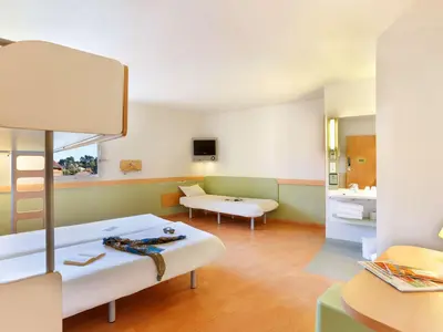 a large room with two beds and a couch at First Inn Hotel in Apt