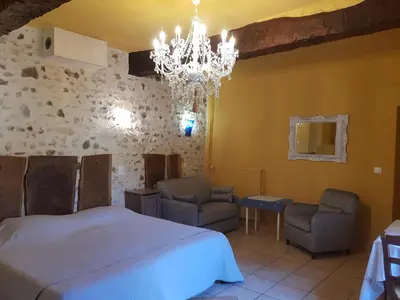 a bedroom with a bed and two chairs and a chandelier at Chambres & Tables d'hôtes Moulin de Lavon in Gargas