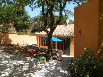 a house with a tree and a blue umbrella at Villa Célestine in Roussillon
