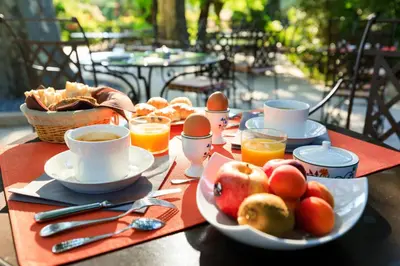 a table with a breakfast of eggs and fruit on it at Hôtel Mas Valentine in Saint-Rémy-de-Provence