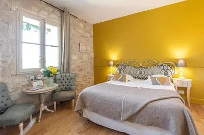 a bedroom with a large bed and a yellow wall at Hôtel Mas Valentine in Saint-Rémy-de-Provence
