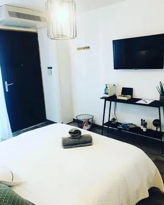 a bedroom with a white bed and a flat screen tv at Appart Hôtel Cézanne in Aix-en-Provence