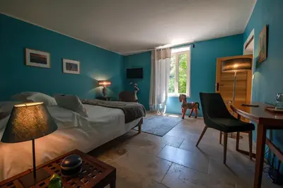 a bedroom with blue walls and a bed and a desk at La Ressence Luberon in Bonnieux