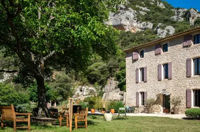 a stone building with a table and chairs in a yard at La Ressence Luberon in Bonnieux