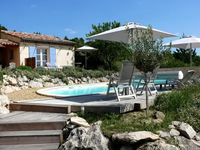 a swimming pool with two chairs and an umbrella at AU PIED DU VENTOUX in Flassan