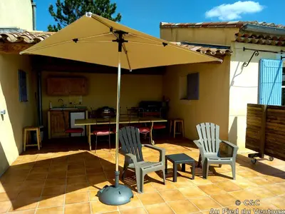 an umbrella on a patio with two chairs and a table at AU PIED DU VENTOUX in Flassan