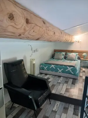 a bedroom with a bed and a leather chair at les cerisiers de stella in Blauvac